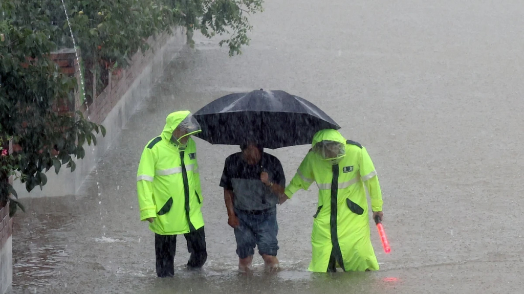 Cảnh sát hỗ trợ người dân di chuyển qua đoạn đường ngập lụt ở Changnyeong, tỉnh Nam Gyeongsang, Hàn Quốc 