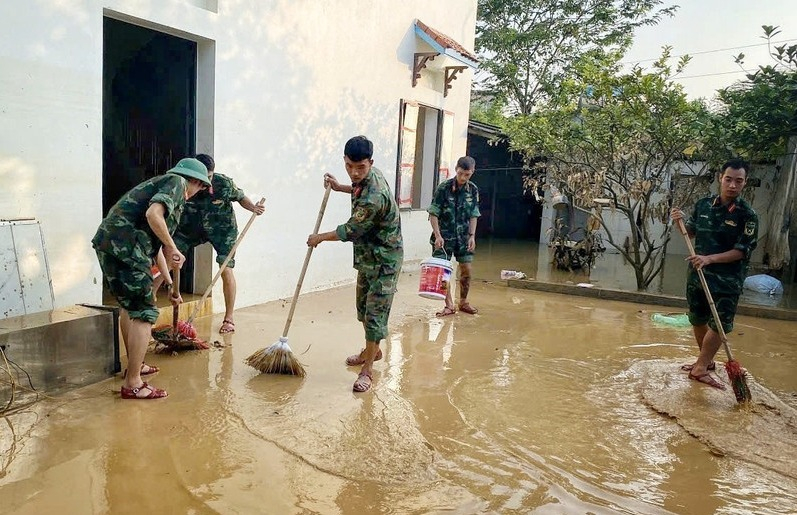 Cán bộ chiến sỹ Trung đoàn 95 giúp người dân dọn dẹp khắc phục hậu quả lũ lụt. (Ảnh: Danh Lam/TTXVN)