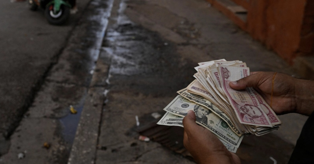 Một người dân địa phương cầm USD và đồng peso Cuba tại thủ đô Havana tháng 8-2025 - Ảnh: REUTERS
