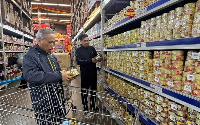 Người dân kiểm tra đồ hộp kỹ trước khi mua. Ảnh Tiến Vĩnh/TTXVN