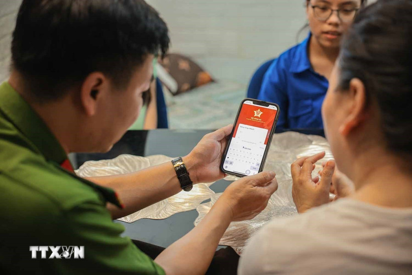 Tổ chuyển đổi số cộng đồng hướng dẫn người dân sử dụng ứng dụng VNeID. Ảnh: Hoàng Hiếu/TTXVN