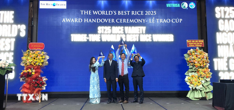 Anh Hùng lao động Hồ Quang Cua cùng các con nâng cao cúp "Gạo ngon nhất thế giới" năm 2025 tại buổi lễ. Ảnh: Nguyễn Văn Việt/TTXVN