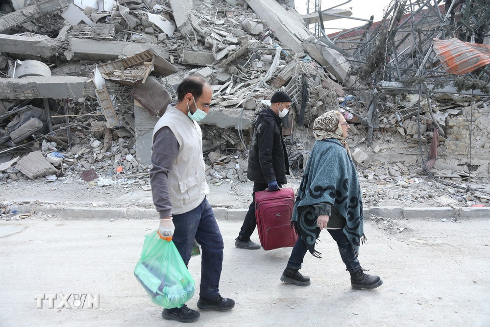 Người dân đi qua đống đổ nát của những tòa nhà bị phá hủy tại Tehran, Iran. (Ảnh: THX/TTXVN)