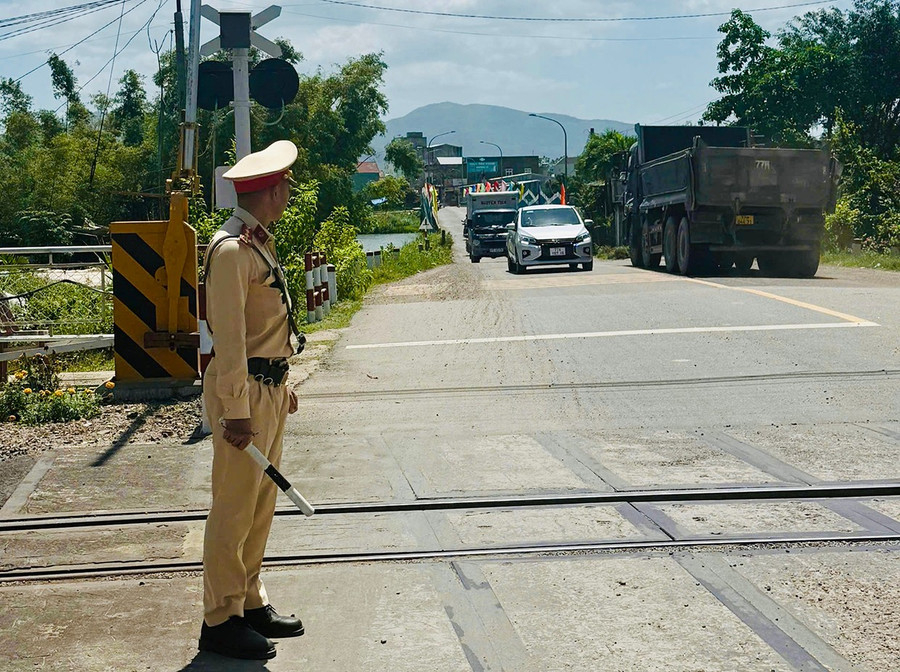 Cảnh sát giao thông hướng dẫn người điều khiển phương tiện tham gia giao thông đúng quy định tại đường ngang có cần chắn tự động.