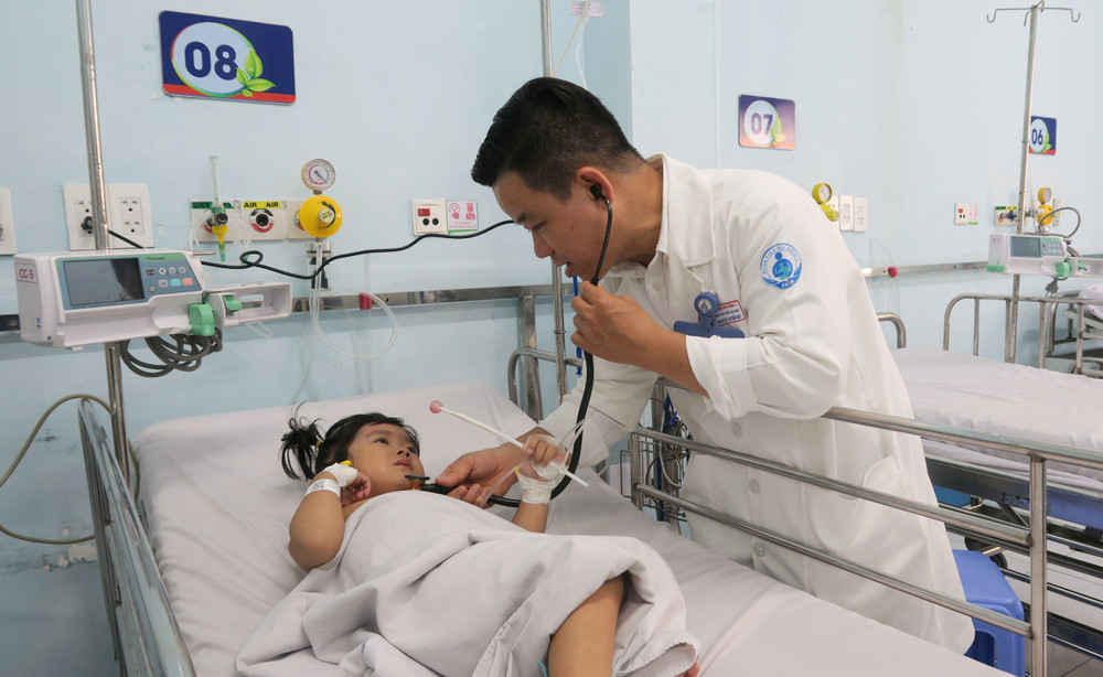 Bác sỹ Bệnh viện Nhi đồng 1 Thành phố Hồ Chí Minh, khám cho bệnh nhi mắc tay chân miệng. Ảnh: TTXVN