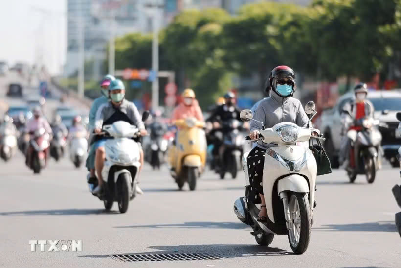Người dân sử dụng khẩu trang, áo chống nắng giúp tránh nóng bức khi tham gia giao thông. Ảnh: TTXVN