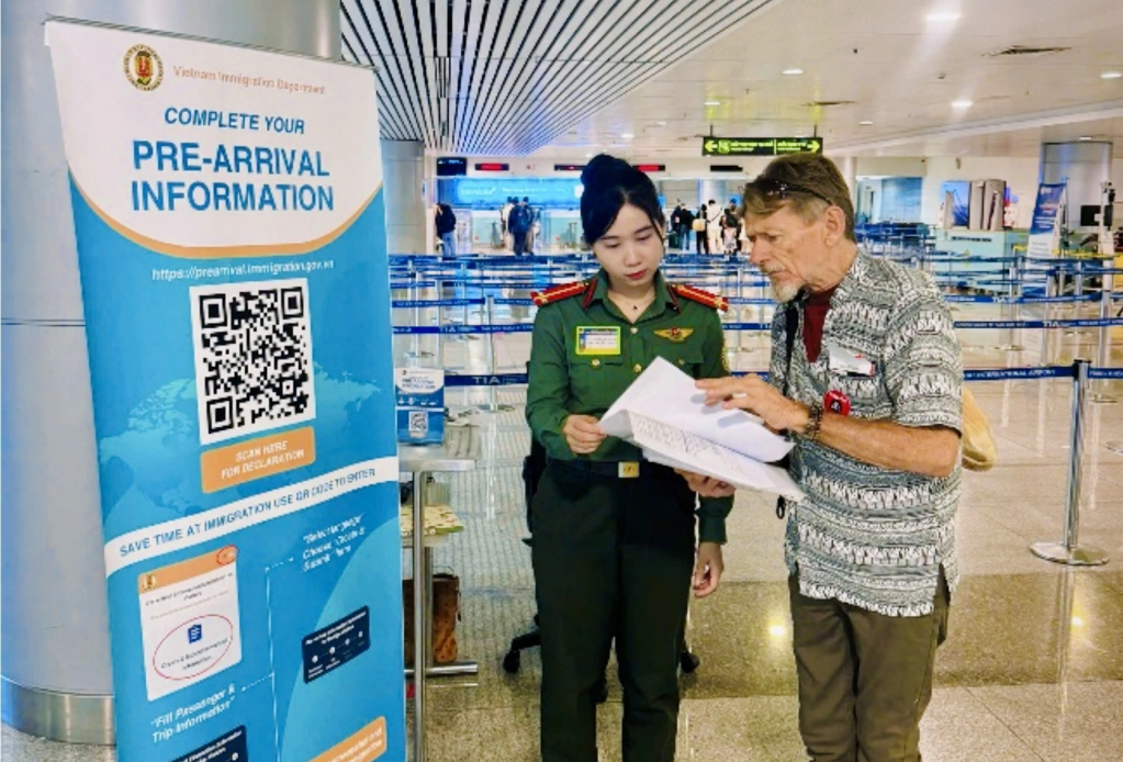 Lực lượng quản lý xuất nhập cảnh hướng dẫn người nước ngoài khai báo thông tin chuyến đi tại sân bay Tân Sơn Nhất. Ảnh: NHUNG NGUYỄN